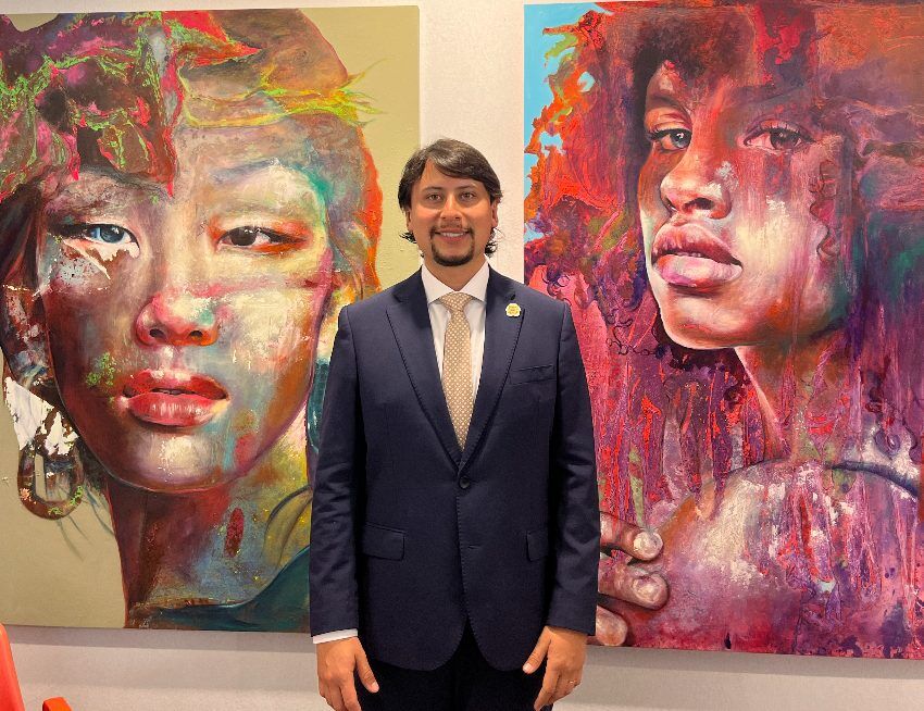 Organizador del certamen frente a dos retratos de gran formato