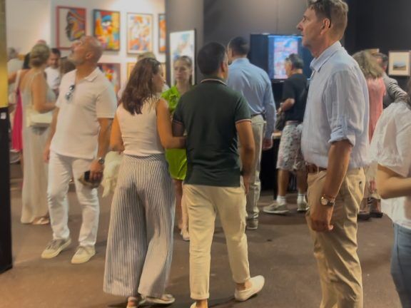 Visitantes recorriendo los pasillos de la feria frente a las obras expuestas