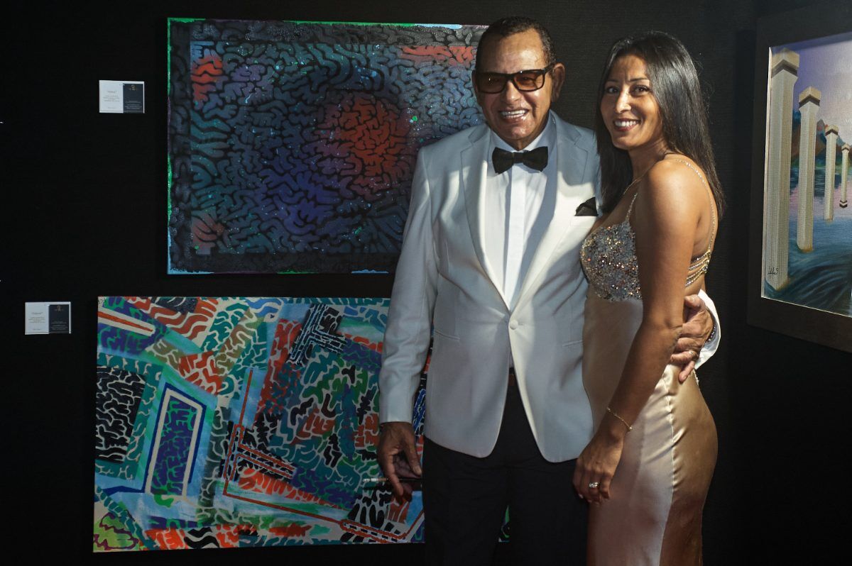 Pareja de gala junto a dos obras abstractas en el stand de la feria