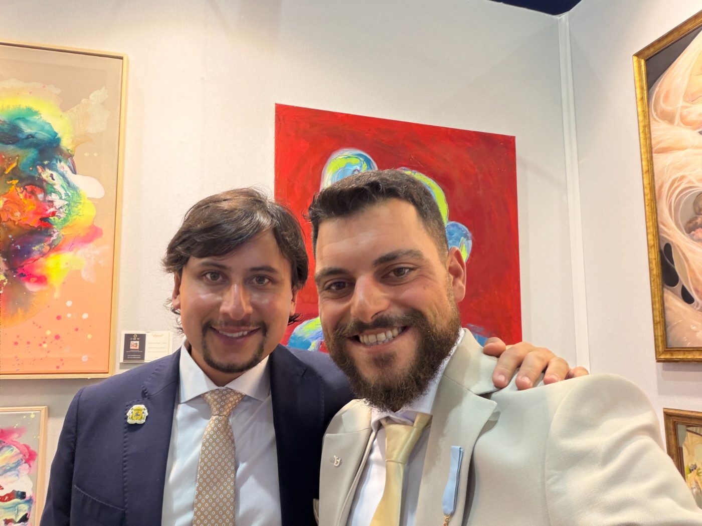 Dos organizadores en el stand de la feria, frente a obras expuestas